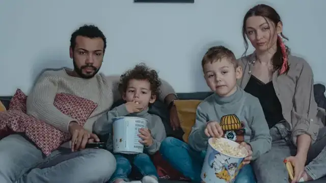 Family sitting on a sofa watching television together