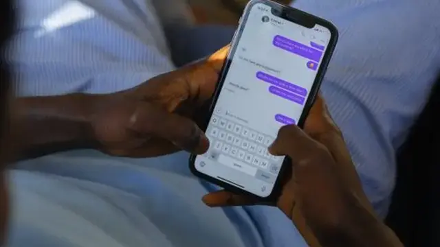 Person typing on a smartphone in a dark room