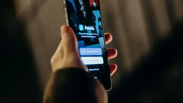 Hand holding a smartphone showing apps on screen